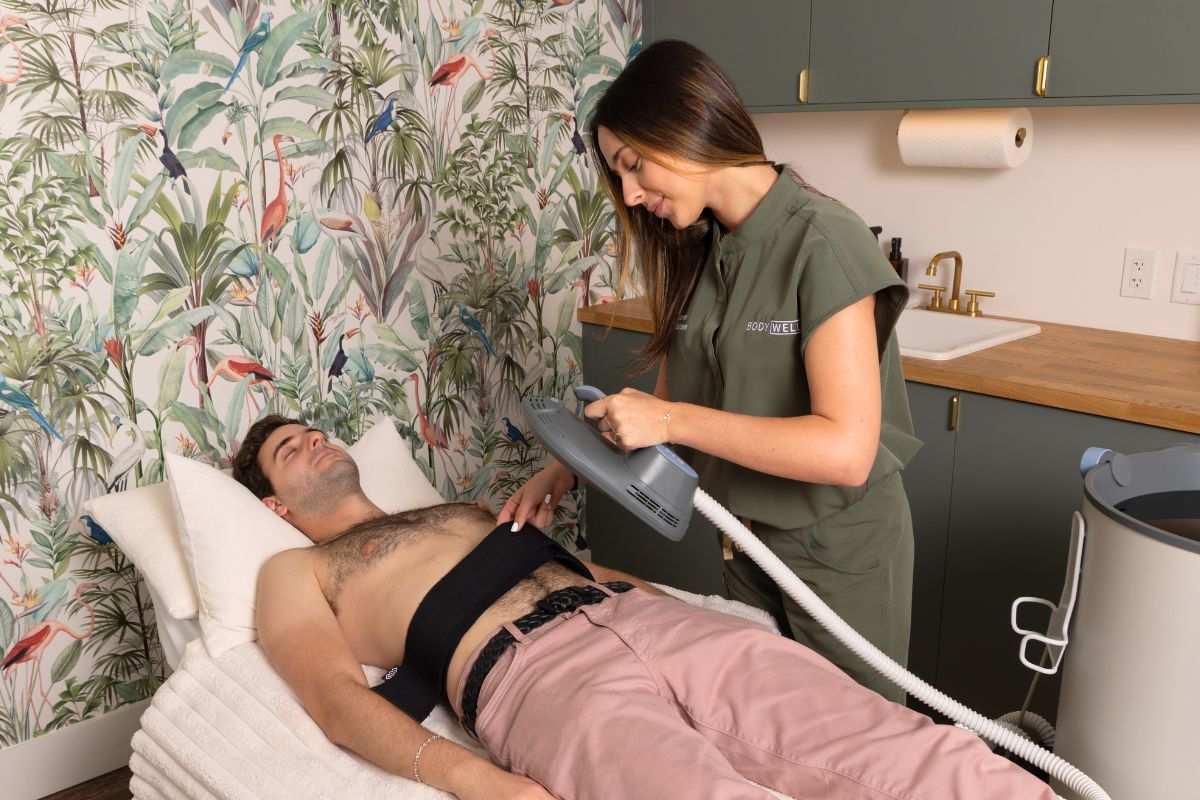 Clinician applying Emsculpt Neo device to a male patient's abdomen during a body contouring session in a medspa.