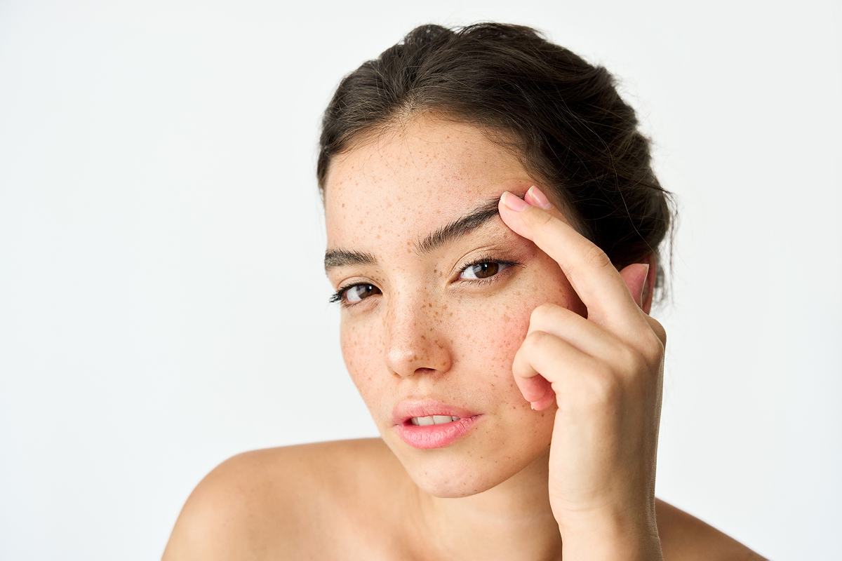 Woman with hooded eyes gently lifting brow to show potential Botox treatment area for non-surgical eye lift.
