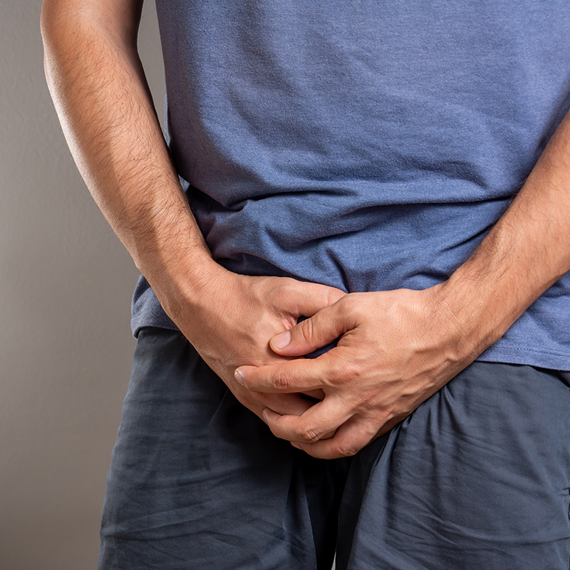 Man clutching lower abdomen, representing relief from overactive bladder symptoms with Botox treatment.