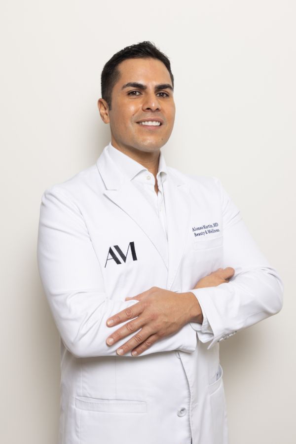 Dr. Alonso Martin wearing a white coat and smiling confidently, known for expert lip filler treatments in Miami Beach.
