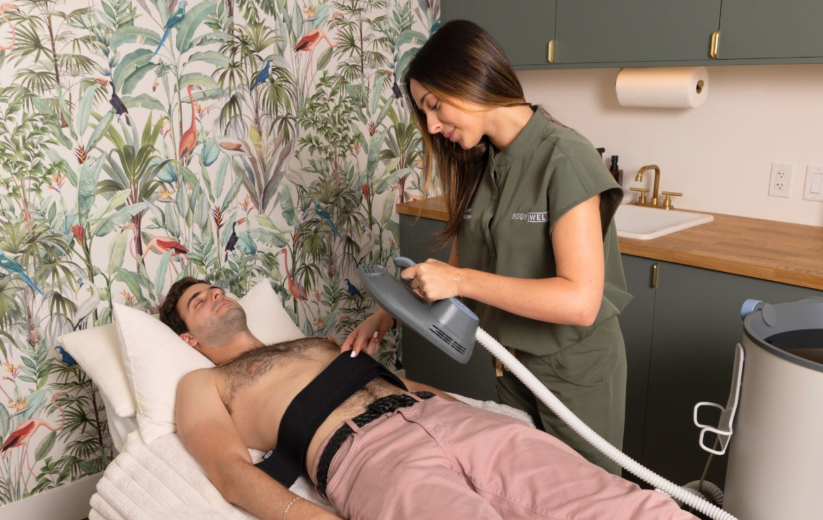 Clinician applying Emsculpt Neo device to a male patient's abdomen during a body contouring session in a medspa.