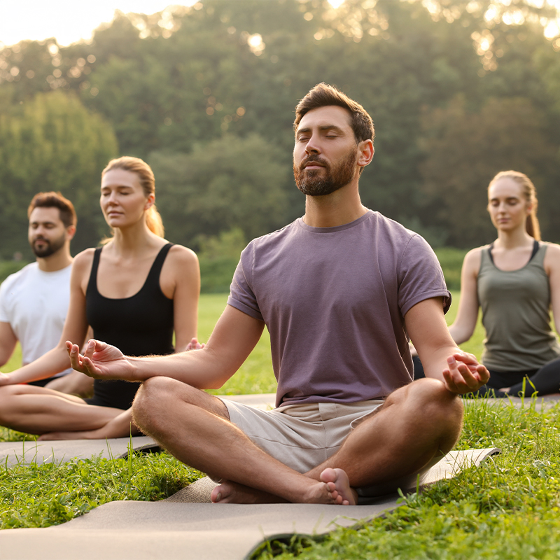 Group practicing seated yoga outdoors, promoting flexibility and balance as safe post-Botox activities