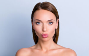 Woman with smooth, plump lips making a pout face after receiving lip filler treatment for enhanced volume and shape.