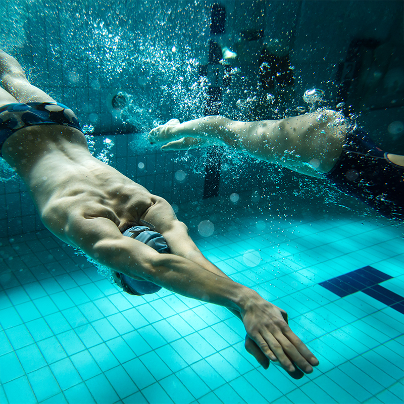 Two swimmers underwater in a pool, demonstrating light cardio as a gentle post-Botox fitness activity