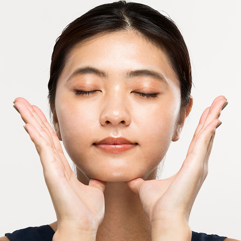 Woman touching her jaw with eyes closed, representing TMJ disorder relief through Botox muscle relaxation therapy.