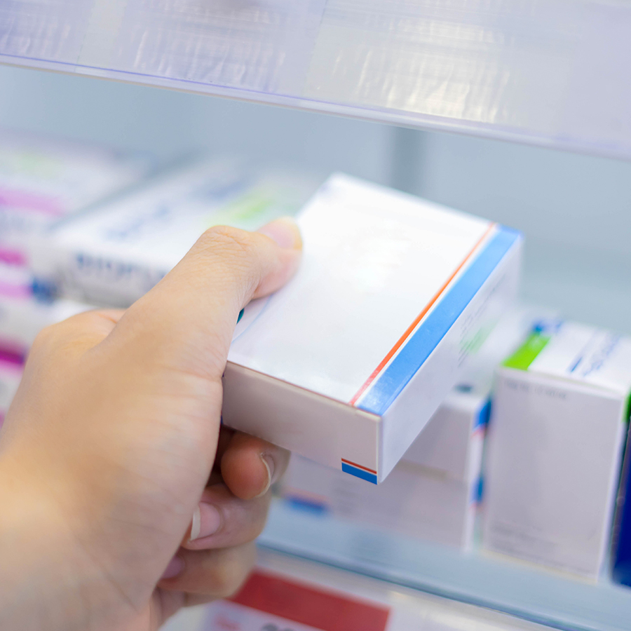 Hand selecting hormone therapy box from pharmacy shelf, illustrating GHRPs' role in natural hormone stimulation