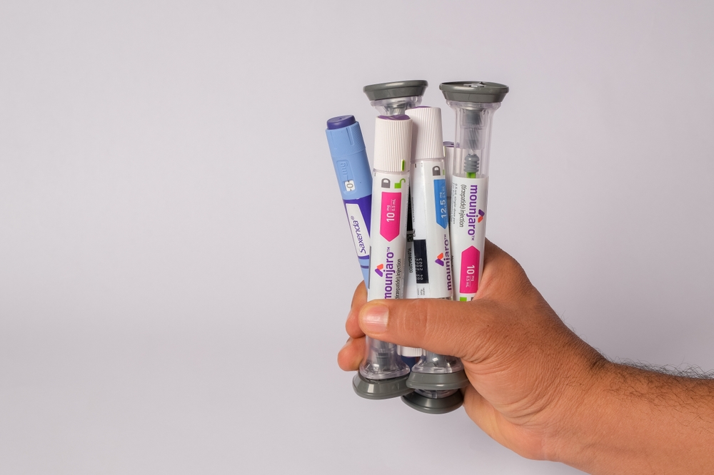 Hand holding multiple Mounjaro and Saxenda injection pens used for long-term weight loss and diabetes treatment.