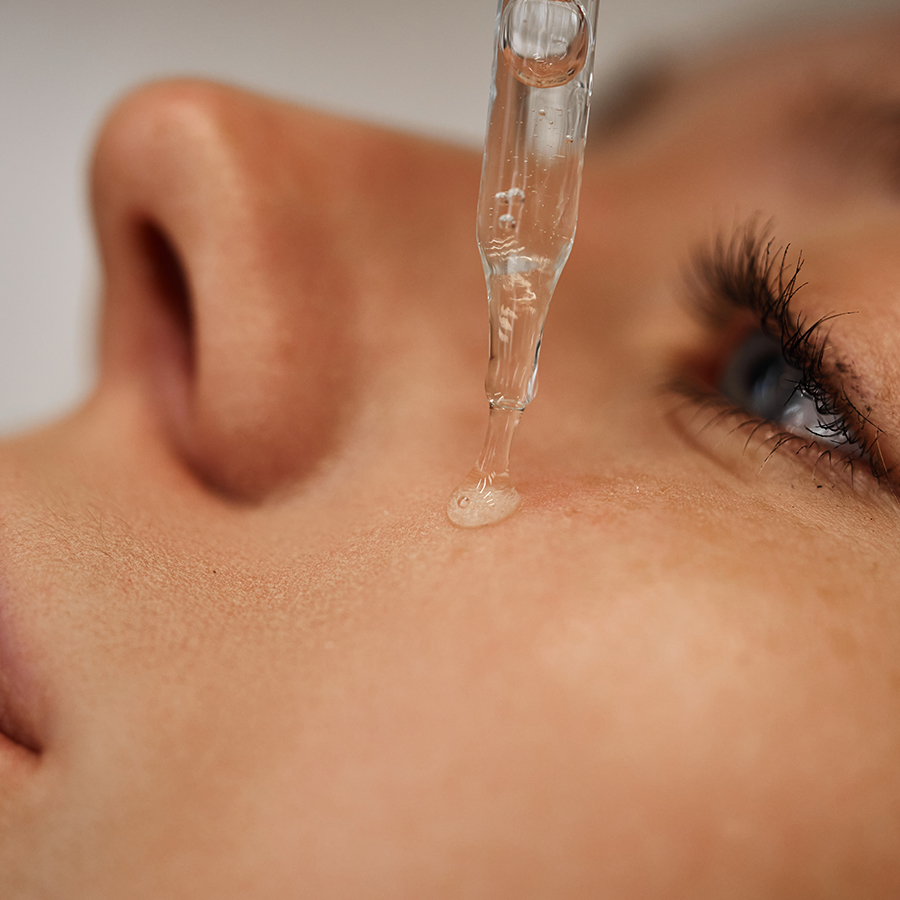 Dropper applying peptide serum to cheek, illustrating deep-acting cellular repair compared to surface-level skincare