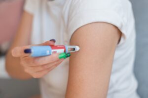 Person self-injecting Ozempic or Mounjaro into upper arm for weight loss treatment.