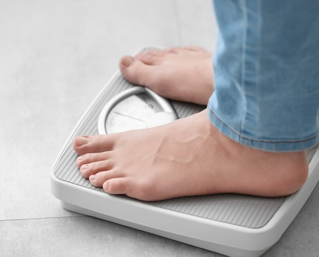 Close-up of person standing on scale showing weight loss progress from semaglutide injections and GLP-1 effects.