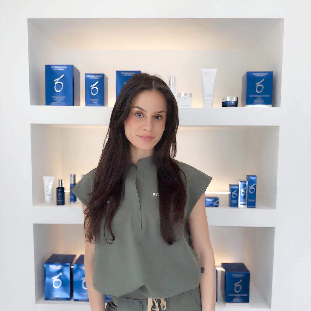 Woman standing in front of illuminated shelves displaying medical-grade skincare products at BODYWELLE in Miami Beach.