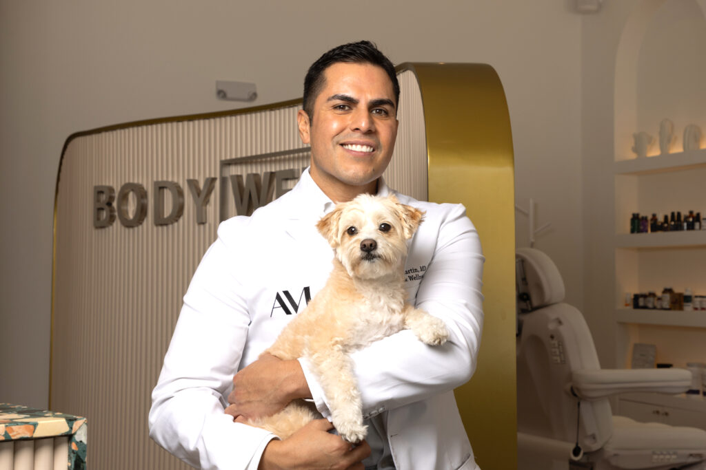 Dr. Martin holding a dog inside BODYWELLE clinic, emphasizing compassionate cognitive support and brain health care