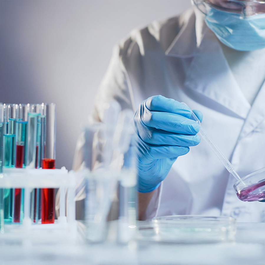 Scientist wearing gloves and mask handling pipette in lab, analyzing mitochondrial function to assess cellular health