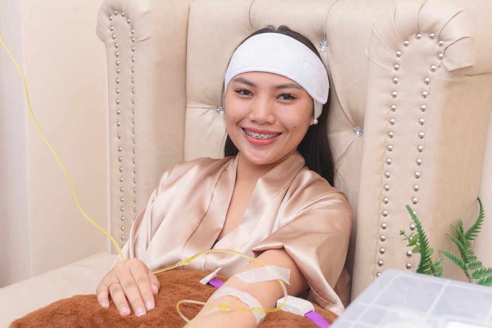 Woman receiving glutathione IV therapy while relaxing, promoting liver detoxification and immune system support.