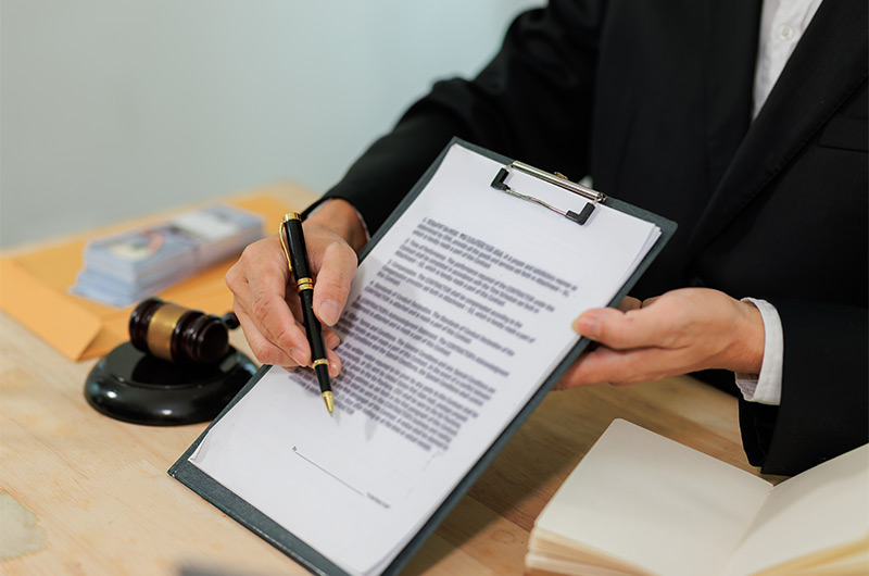Person in formal attire holding and signing a policy acknowledgment form on a clipboard in a clinic setting.