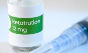 Retatrutide 12 mg vial with syringe on medical surface, representing investigational weight loss medication for obesity treatment.