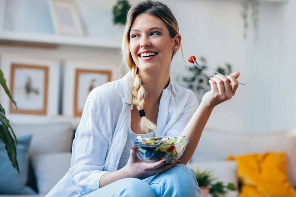 Woman eating a fresh salad, illustrating appetite control and healthy eating supported by GLP-1 medications