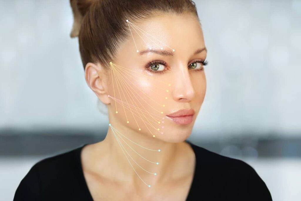 A side-profile view of a woman with hair tied up, featuring multi-colored vector graphics mapped across her eyebrow, cheek, jawline, and neck.