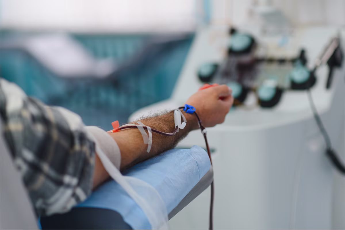 Patient connected to blood-processing tubing during treatment.