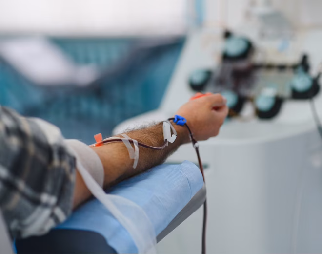 Patient connected to blood-processing tubing during treatment.